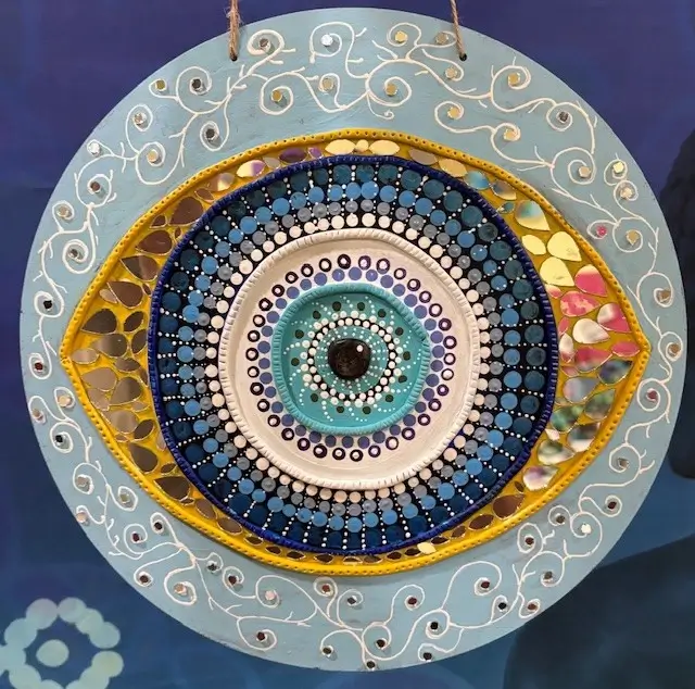 evil eye lippan art style with mirror with colors of blue yellow gold creative art to ward off evil eye